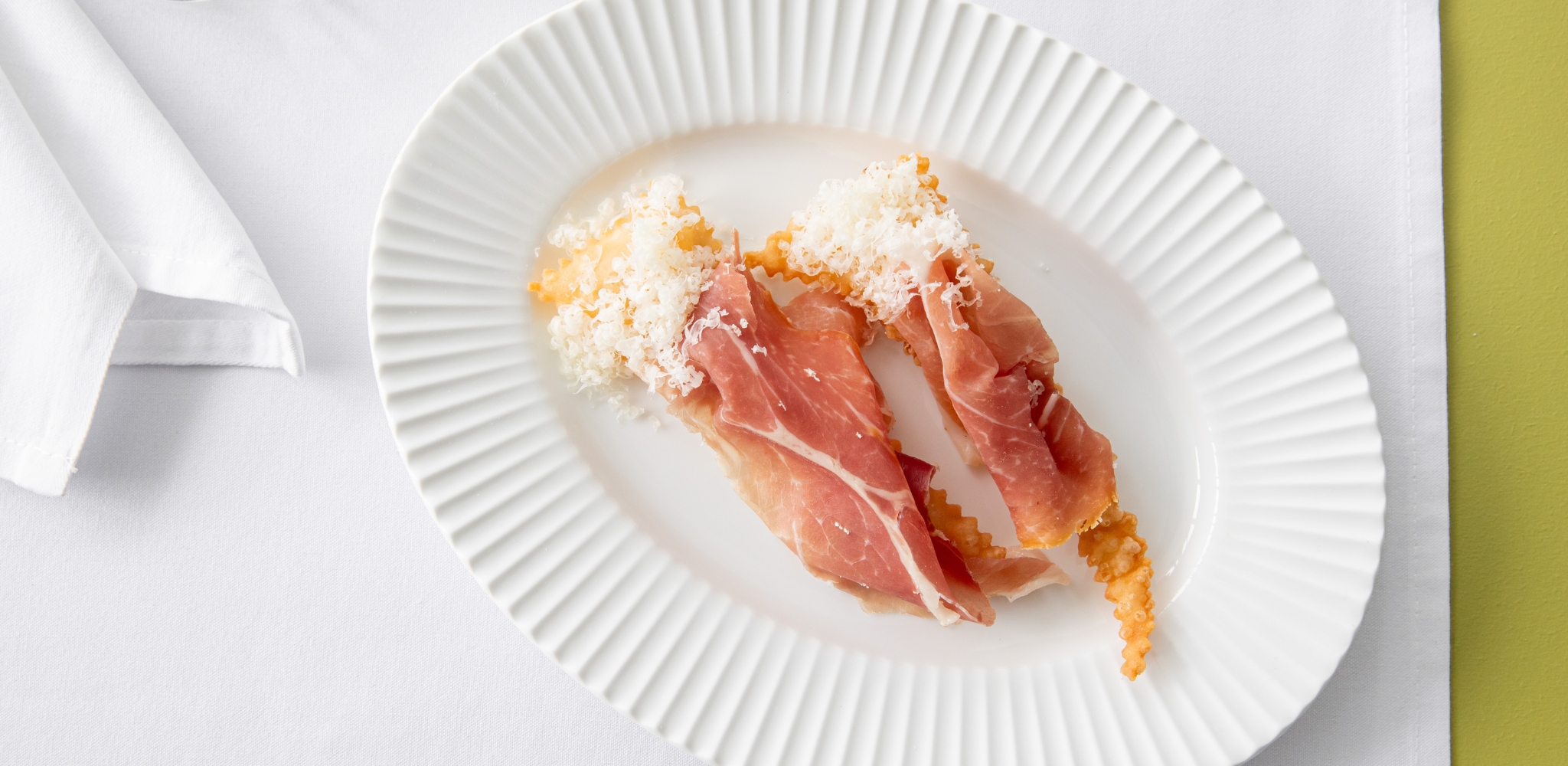 Image of Bistro George's gnocco fritto and San Daniele prosciutto served on a white plate with white napkin.