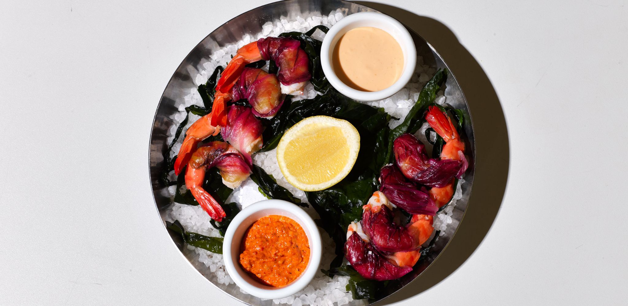 Spencer Gulf King prawns, radicchio, romesco, sauce marie-rose and lemon served on a silver tray on salt and beetroot leaves