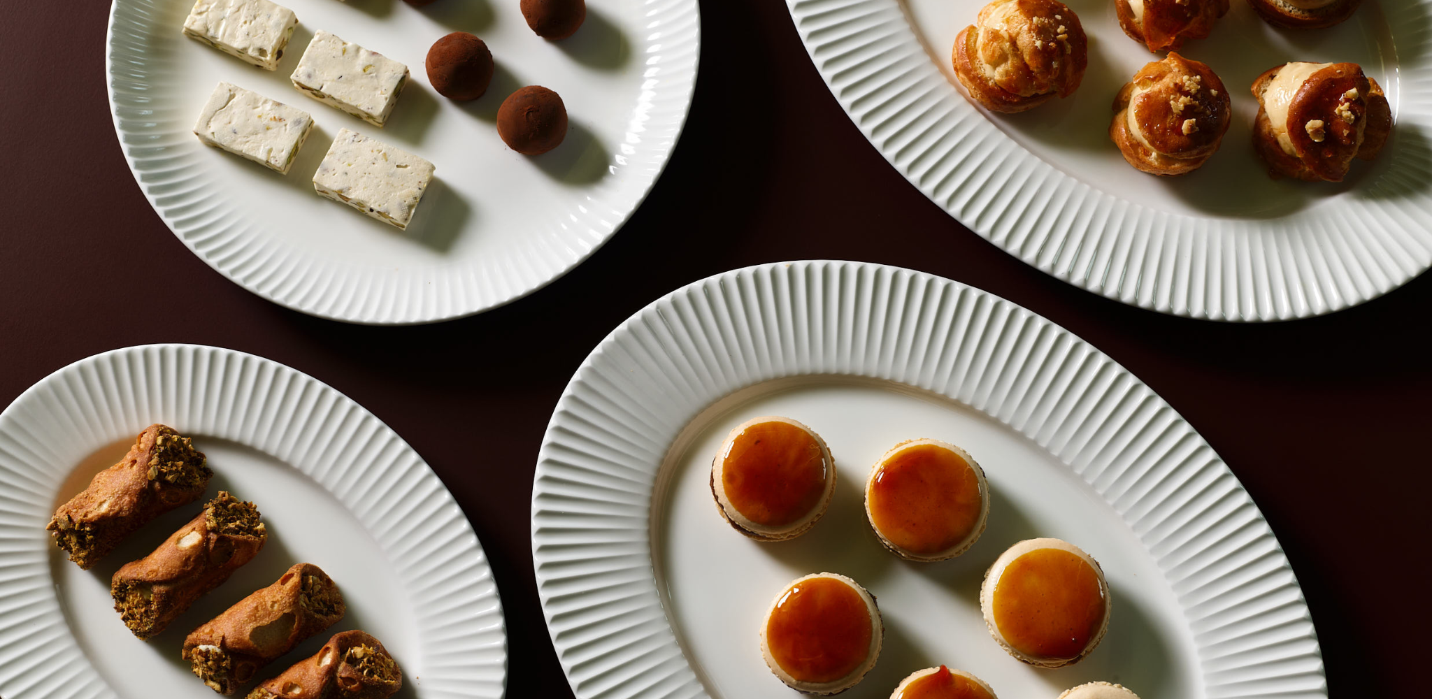 A selection of premium dessert canapes such as Cannoli, mascarpone mousse, pistachio, Salted caramel macaron, Lemon meringue tartlet, Pistachio, almond nougat